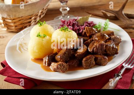 Gulasch di manzo squisito servito con gnocchi di patate e crauti sul piatto durante la cena nel ristorante Foto Stock