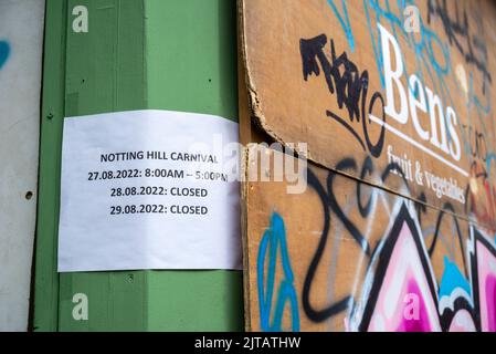 Notting Hill, Londra, Regno Unito. 29th ago, 2022. Il più grande festival di strada d’Europa è tornato nelle strade di Notting Hill dopo gli anni annullati a causa della pandemia di Covid. Ballerini esotici a tema giamaicano e gruppi musicali sfilavano per le strade, con cibo e intrattenimento di strada in tutta l'area che si aggiungono all'evento. La Grand Parade si svolge il lunedì delle festività come il culmine del festival di tre giorni, che ha avuto inizio nel 1966. Le aziende locali e le proprietà sono imbarcati per la protezione. Negozio di frutta e verdura coperto da lenzuola di legno, chiuso per l'evento. Avviso con chiuso Foto Stock