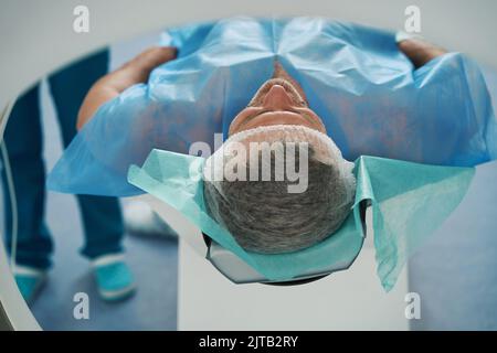 L'uomo si trova nella camera del tomografo per la diagnosi dell'addome Foto Stock