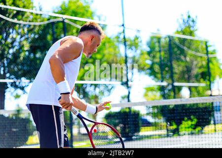 Uomo caucasico senior che gioca a tennis sul campo con racket tennis luce diurna all'aperto all'aria aperta Foto Stock