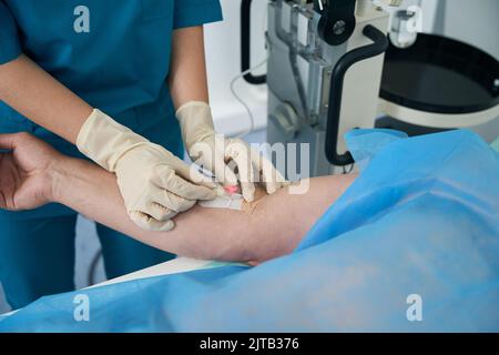 Il medico mette gocciolamento sul paziente nella stanza di manipolazione al centro medico Foto Stock