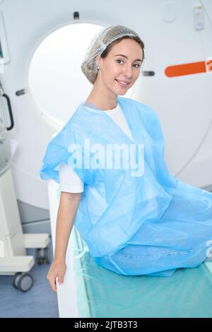 Il paziente in tuta protettiva si appoggia sullo sfondo del tomografo Foto Stock