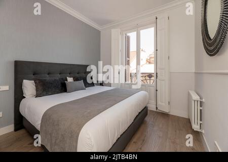 Letto matrimoniale con testata in legno e copriletto trapuntato in bianco  camera da letto con grande ombra leggera Foto stock - Alamy