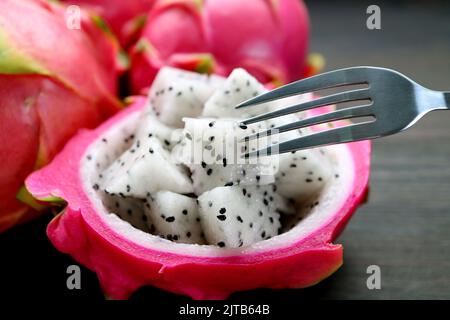 Forca per primo piano che raccoglie un pezzo di frutta fresca e matura Juicy Dragon Fruit Foto Stock