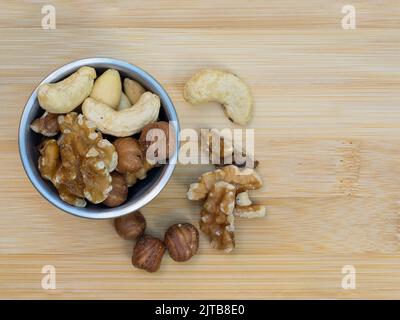 piatto lay vista noci miste in acciaio inox piatto e tavolo di bambù Foto Stock