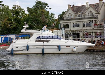 Un uomo attracca una barca Sealine 450 al di fuori di un pub inglese sul fiume Tamigi a Walton, Surrey Foto Stock