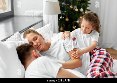 ragazza felice sveglia i suoi genitori nella mattina di natale Foto Stock