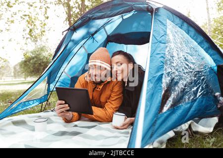 coppia con pc tablet bere tè all'interno della tenda Foto Stock