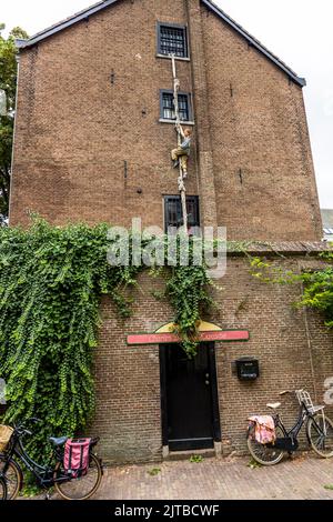 Una figura si arrampica fuori da una finestra con sbarre su una corda di stoffa al Charles Dickens Kabinet nel Bergkwartier, il quartiere storico della vecchia città di Deventer, una delle nove città anseatiche storiche sull'IJssel, provincia di Overijssel, Paesi Bassi. Il piccolo museo Dickens occupa un'ex prigione femminile su Walstraat, ancora riconoscibile dalle sue finestre con sbarre. Foto Stock