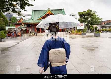 Una geisha giapponese che indossa un kimono tradizionale, cammina intorno al Santuario di Kanda Myojin in un giorno di pioggia, a Chiyoda, Tokyo, Giappone. Foto Stock