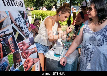 La ragazza sta facendo tatuaggio sul braccio della donna nel festival della città di Carnikava, Carnikava, Lettonia Foto Stock