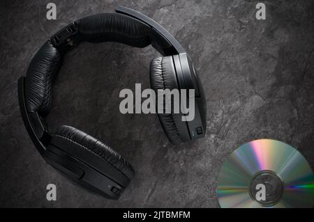 Cuffie wireless nere con Compact Disk su banco in granito orizzontale Foto Stock