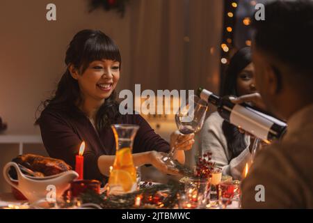 Felice gli amici a bere vino rosso alla festa di natale Foto Stock