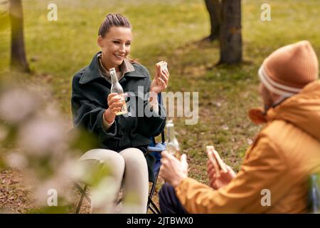 coppia bevendo birra con panini al campo tenda Foto Stock