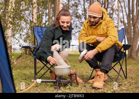 coppia cucinare cibo su bruciatore a gas al campo tenda Foto Stock