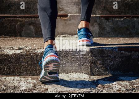 Sprinter maschio che indossa scarpe da running sullo sfondo delle scale in cemento. Sport e fitness atleta runner allenamento allo stadio Foto Stock