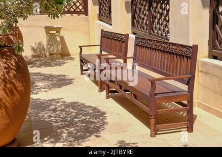 Panca in legno d'orientamento fatta a mano con motivi floreali arabeschi ornamentali intagliati nel cortile interno della villa medio orientale Foto Stock