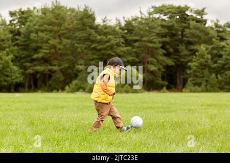 ragazzino con la palla che gioca a calcio al parco Foto Stock