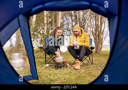coppia cucinare cibo su bruciatore a gas al campo tenda Foto Stock