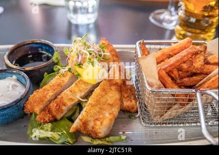 Tonkatsu servito con patatine fritte dolci e aioli. Il tonkatsu è un piatto giapponese composto da cotoletta di maiale fritta e impanata. Foto Stock