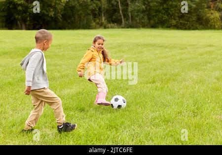 bambini piccoli con la palla che gioca a calcio al parco Foto Stock