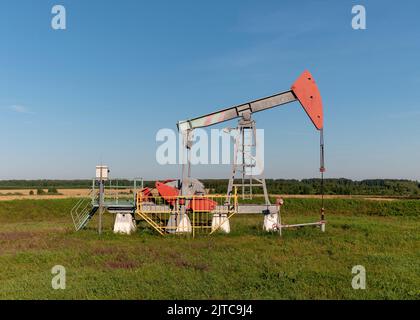 Pozzo di petrolio e gas in giacimento petrolifero, sagomato contro il cielo blu. Foto Stock