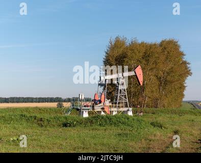 Pozzo di petrolio e gas in giacimento petrolifero, sagomato contro il cielo blu. Foto Stock