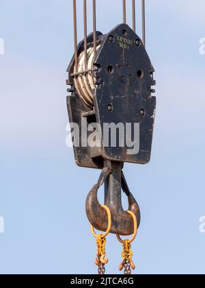 Il gancio della gru con strisce rosse e bianche pensili, cielo blu in background. Foto Stock