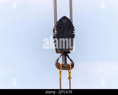 Il gancio della gru con strisce rosse e bianche pensili, cielo blu in background. Foto Stock