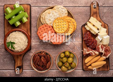 Fotografia alimentare di antipasto, hummus, sedano, cracker, formaggio, cheddar brie, salame, prosciutto, olive Foto Stock