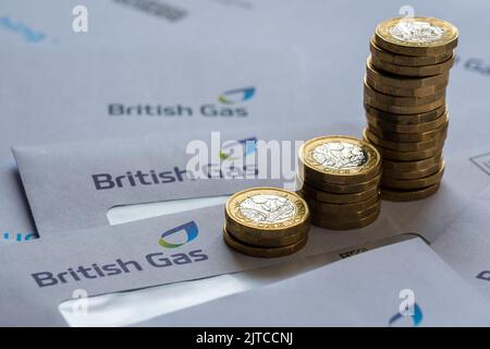 Pile di una moneta in sterline sulla cima delle fatture British gas nelle buste. Concetto per la crisi energetica e l'aumento dei prezzi del gas nel Regno Unito. Stafford, Regno Unito, Augus Foto Stock