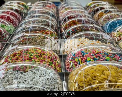 File di caramelle colorate e zuccherate sono esposte in contenitori di plastica presso il chiosco per gli alimenti del centro commerciale. Foto Stock