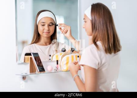 ragazza adolescente applicare mascara in bagno Foto Stock