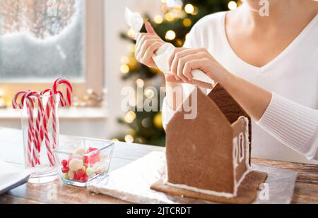 Close up della donna che fa gingerbread house Foto Stock