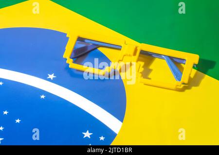 Occhiali con colori brasiliani, giallo e blu verde, concetto di coppa del mondo con sfondo giallo. Foto Stock