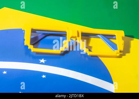 Occhiali con colori brasiliani, giallo e blu verde, concetto di coppa del mondo con sfondo giallo. Foto Stock