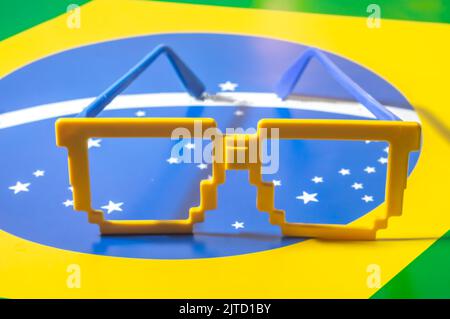 Occhiali con colori brasiliani, giallo e blu verde, concetto di coppa del mondo con sfondo giallo. Foto Stock