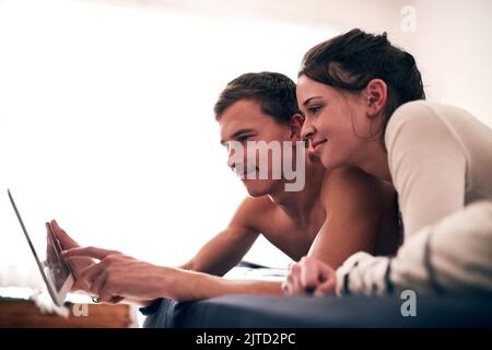 Il sabato è il giorno del piumino, una giovane coppia trascorre una giornata pigra a letto con il tablet. Foto Stock