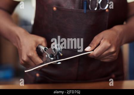 Primo piano di foratura artigianale femminile in cintura fatta a mano in negozio di pelletteria, spazio copia Foto Stock