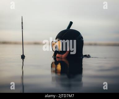 Maschio subacqueo pesca spearfishing nel mezzo dell'oceano. Pescatore che tiene la pistola mentre è immerso in acqua di mare. Foto Stock