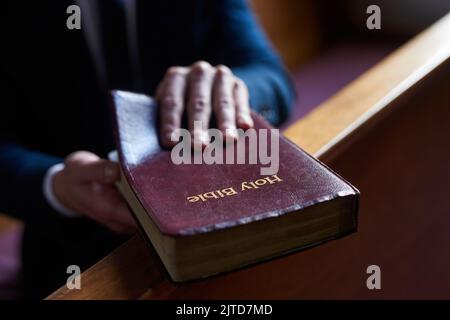 Leggere il buon libro. Un uomo che apre una bibbia mentre siede in un pisello in chiesa. Foto Stock