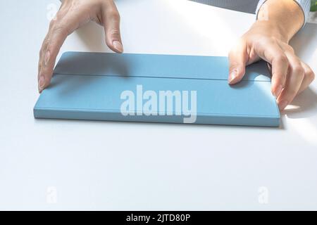 Le mani di una ragazza che tiene una tavoletta in una custodia. Preparazione per lavorare su un tablet Foto Stock