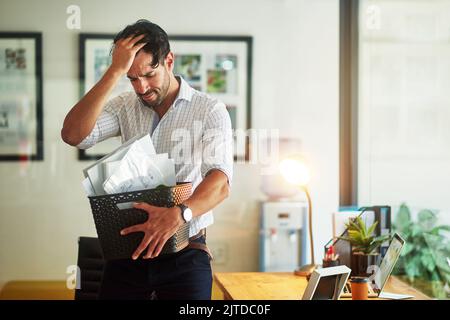 Le sue peggiori paure sono avverate: Un uomo d'affari stressato che tiene la sua scatola di beni dopo essere stato licenziato dal suo lavoro. Foto Stock