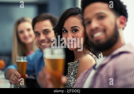 Lasciate che i tempi buoni rotolino. Ritratto di un gruppo di amici felici sorseggiando un drink in un bar. Foto Stock