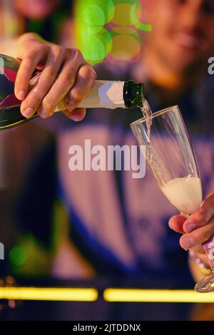 Per iniziare la festa. Primo piano di una persona che versa champagne in un bicchiere. Foto Stock