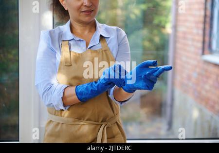 bella donna indossando i guanti di gomma prima di pulire la cucina, lavare  i piatti a casa. bella donna sorridente preparazione per la pulizia della  casa Foto stock - Alamy