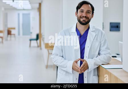 Amichevole medico generico maschile che indossa l'uniforme medica in piedi nella moderna clinica medica, ritratto. occupazione medica Foto Stock