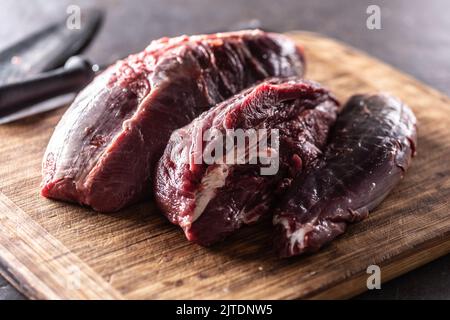 Pezzi di stinco di manzo crudo posti su un tagliere di legno. Foto Stock