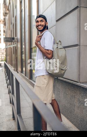 Un bell'uomo sorridente con uno zaino in strada Foto Stock