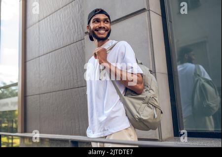 Un bell'uomo sorridente con uno zaino in strada Foto Stock